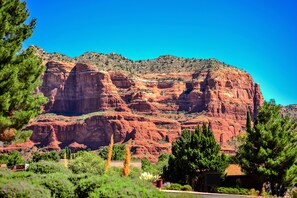 A mountainous landscape with red rock formations and green vegetation.