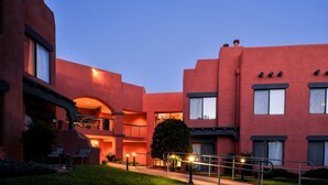 Un edifici amb façana vermella, diversos balcons i una entrada ben il·luminada.