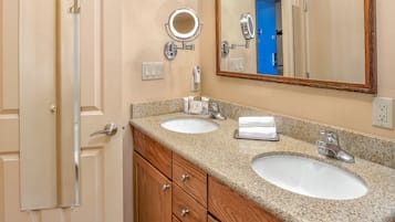 A bathroom with two sinks, a mirror, and wooden cabinets.