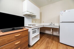 Uma cozinha compacta equipada com televisão de tela plana, micro-ondas, geladeira e armário de madeira.