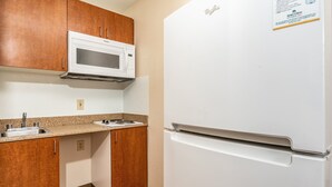 Una cocina con armarios de madera, un microondas blanco y un refrigerador blanco.