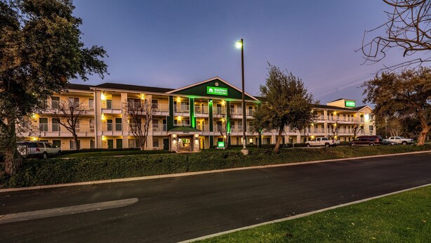 Un motel con varios balcones, un letrero verde y una entrada bien iluminada.