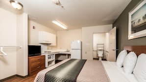 Habitación de hotel con cama, escritorio, refrigerador, microondas y televisión.
