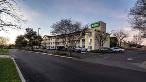 Un motel con un letrero que dice 'Home to Studios' y un estacionamiento con varios autos.