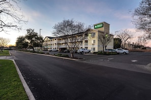 A motel with a sign reading 'Home to Studios' and a parking lot with several cars. - HomeTowne Studios by Red Roof Fresno - West (Fresno)