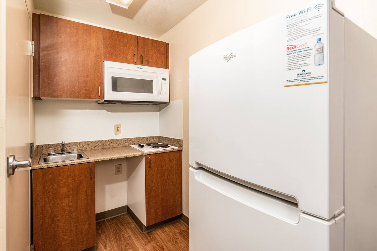 Una cocina compacta con microondas, fregadero y refrigerador.