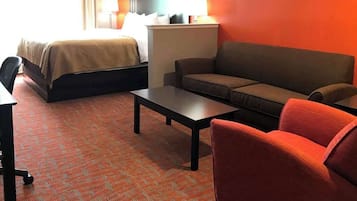 Una habitación de hotel con cama, sofá, mesa de centro y escritorio.