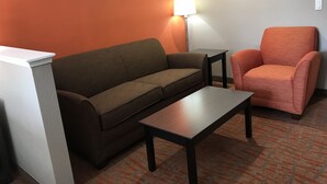 A room with a brown sofa, a small table, a chair, and a lamp.