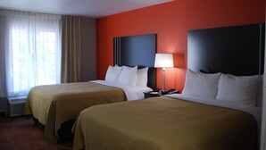 A hotel room with two beds, a nightstand with a lamp, and a window with curtains.