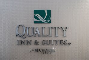 A sign for Quality Inn & Suites with a logo and the name of the hotel.
