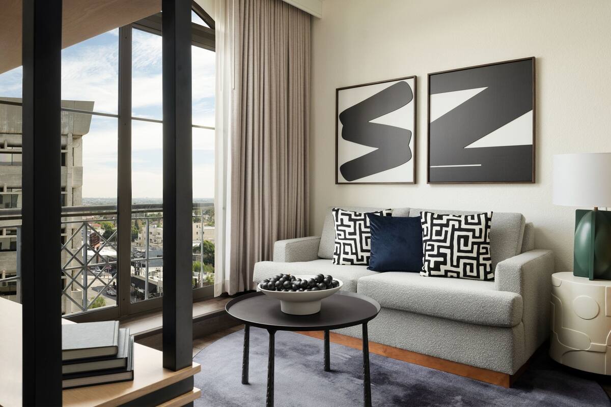A modern living room with a sofa, a coffee table, and two abstract paintings.