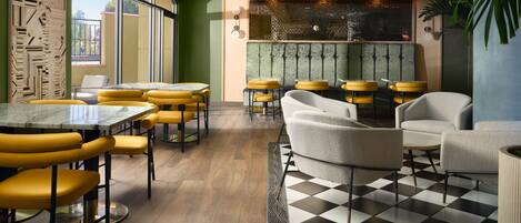 A modern restaurant interior with yellow and grey seating, a checkered floor, and a decorative wall.