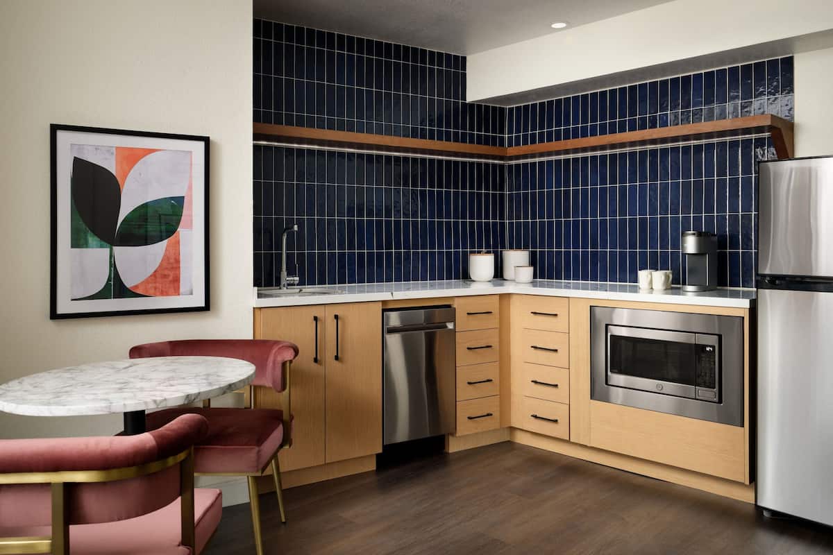 A modern kitchen with blue tiles, stainless steel appliances, and wooden cabinets.