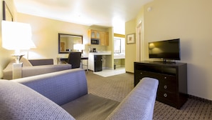 Een hotelkamer met een zithoek, kitchenette, televisie en een bed.