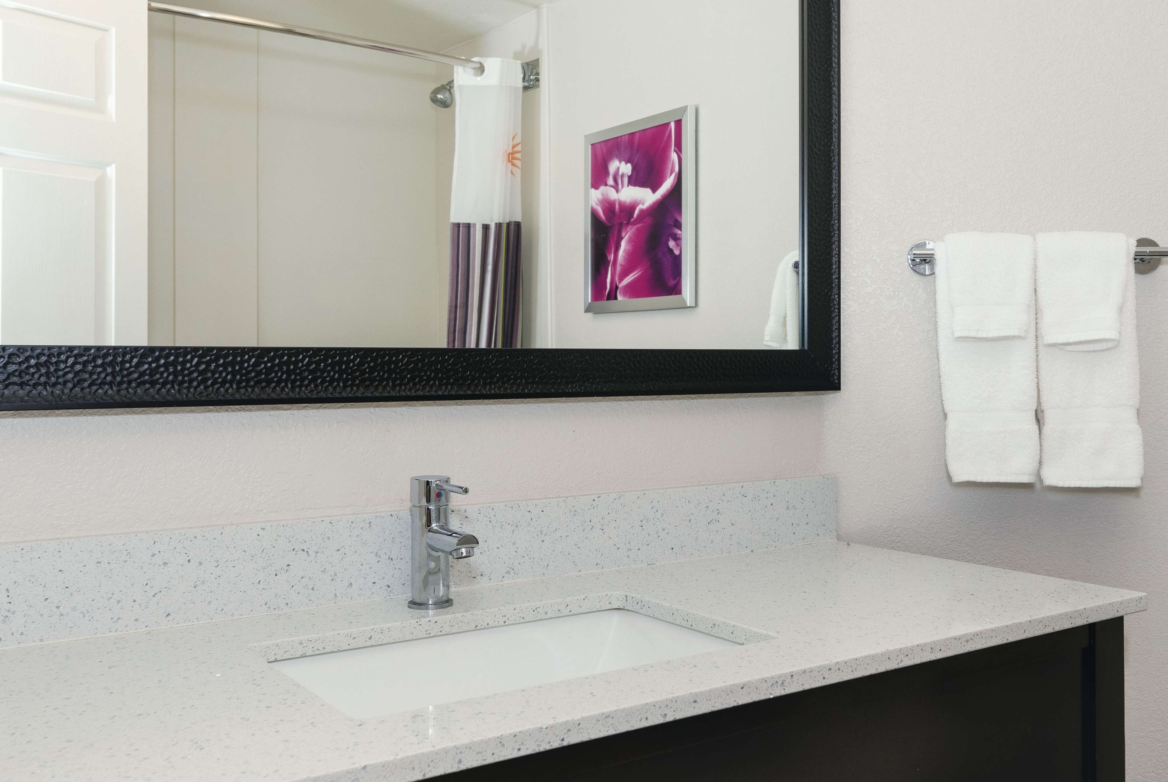 A bathroom with a white sink, a large mirror, and a towel rack with two towels.