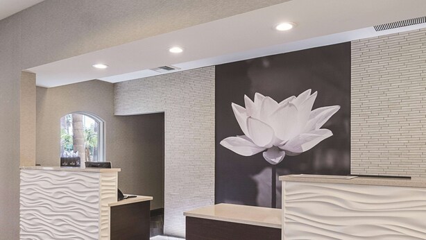 A reception area with two reception desks, one with a textured surface and the other with a smooth surface. A large wall mural of a lotus flower is visible.