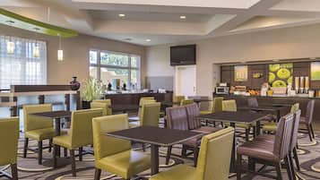 A hotel lobby with multiple seating areas, a reception desk, and a bar area.