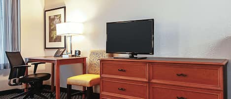 Une chambre d’hôtel équipée d’un bureau, d’une chaise, d’une télévision et d’une commode en bois.