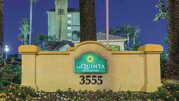 Señal de hotel con el nombre "La Quinta Inn & Suites" y el número "3555" sobre un fondo de cielo nocturno.