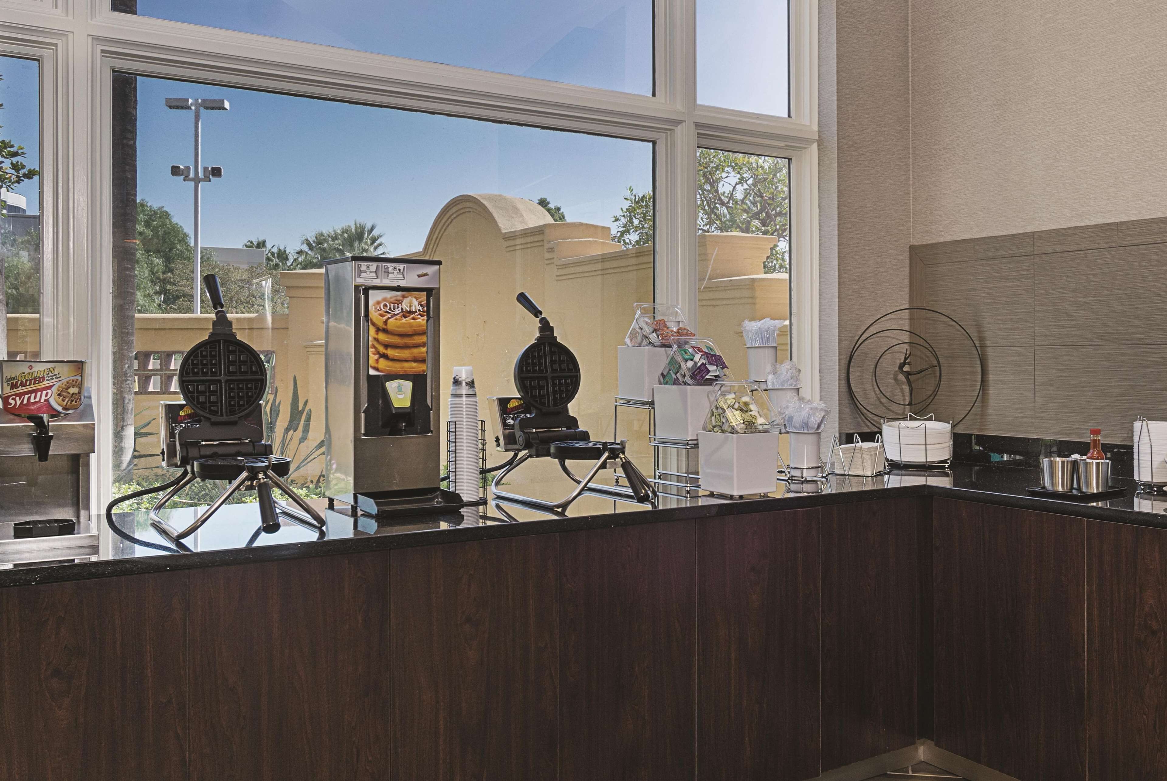 A kitchen counter with waffle makers, a waffle iron, and a waffle display.
