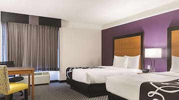 A hotel room with two beds, a desk, and a chair.