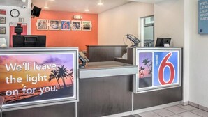 A reception desk with a 'motel 6' sign, a clock, and framed pictures on the wall. - Studio 6 Rancho Cordova, CA (Rancho Cordova)