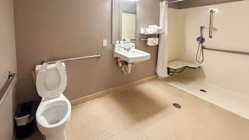 A bathroom with a toilet, sink, mirror, and shower.