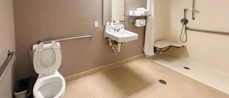 A bathroom with a toilet, sink, mirror, and shower.