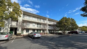 A multi-story building with a parking lot, a red vehicle, and a clear blue sky. - Studio 6 Rancho Cordova, CA (Rancho Cordova)