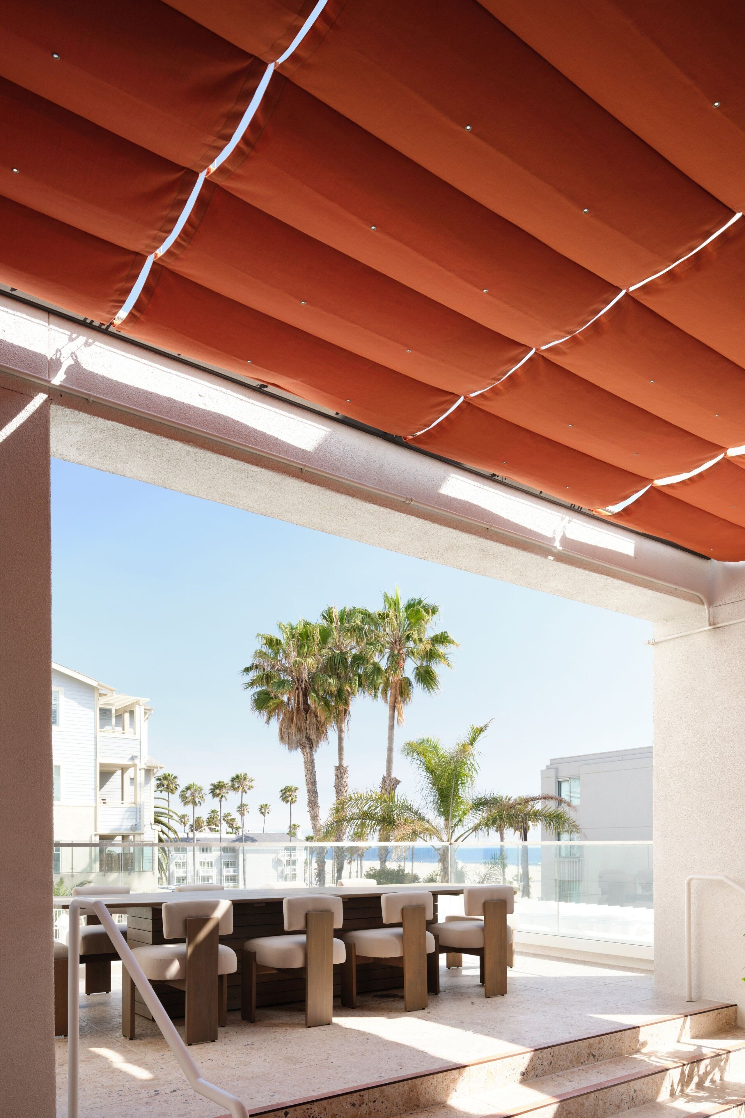 An outdoor seating area with a view of palm trees and buildings.
