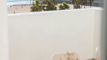 A balcony table with a view of a pier, a Ferris wheel, and a beach.