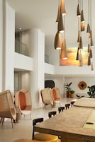 A modern dining area with a high ceiling, pendant lighting, and contemporary chairs.