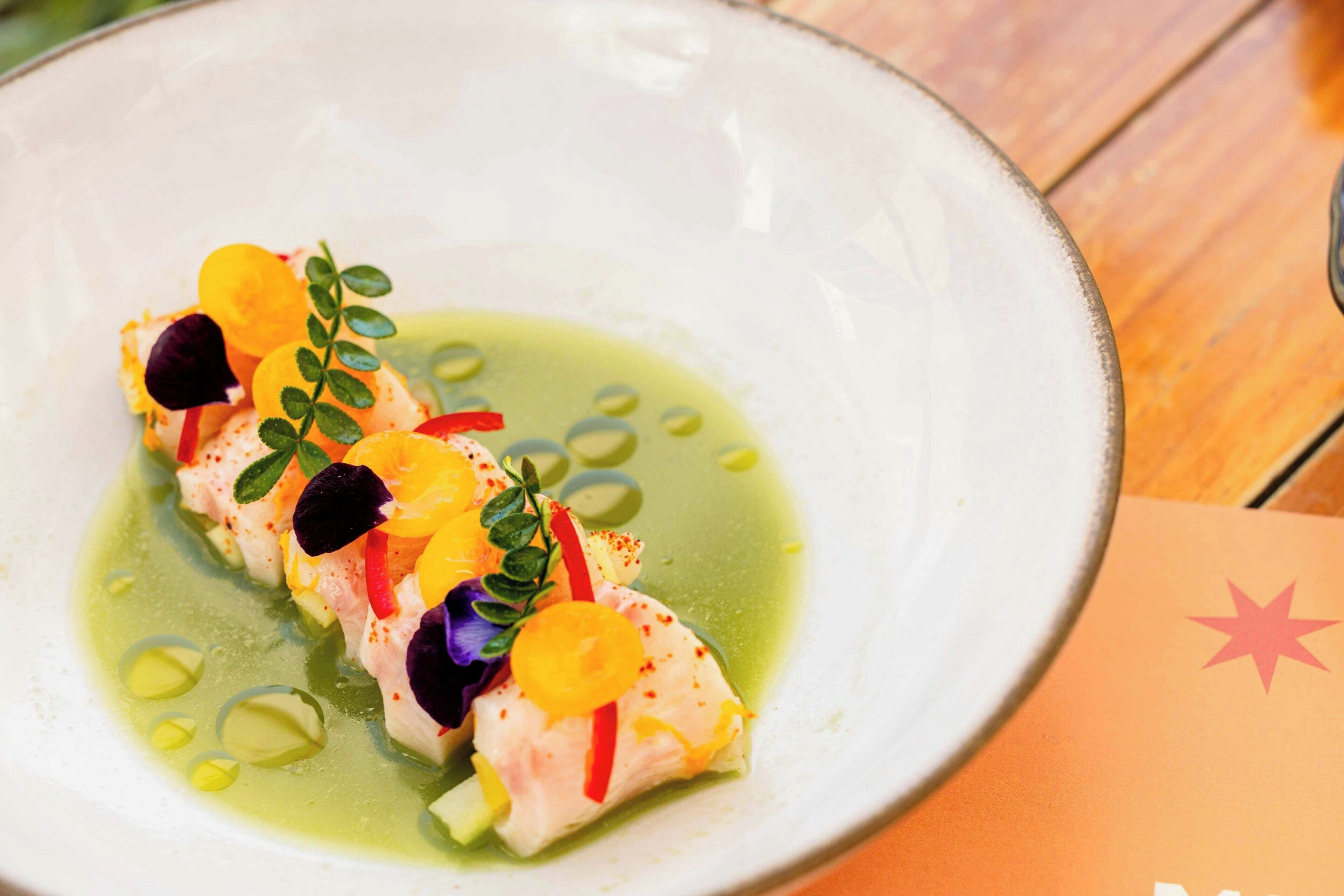 A plate of food with a green sauce and garnishes.