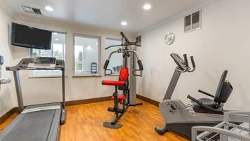 Gimnasio con cinta de correr, máquina de pesas y elíptica.