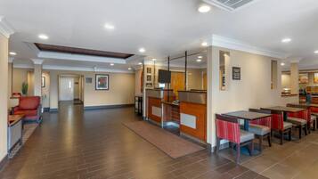 Un hall d’hôtel comprenant un comptoir d’accueil, un espace salon et un coin repas.