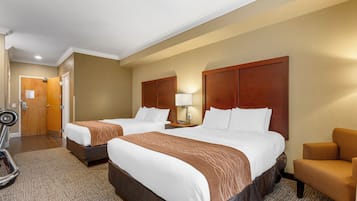 A hotel room with two beds, a desk, a chair, and a treadmill.