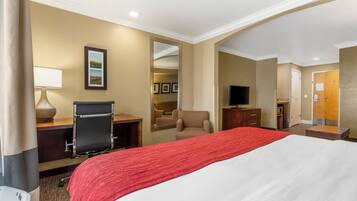 A hotel room with a large bed, a desk with a chair, a TV, and a mirror.