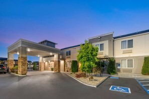 L’entrée d’un hôtel est agrémentée d’une allée couverte, un espace de stationnement comprend une place réservée aux personnes handicapées, et le bâtiment est doté de nombreuses fenêtres et d’un toit plat.
