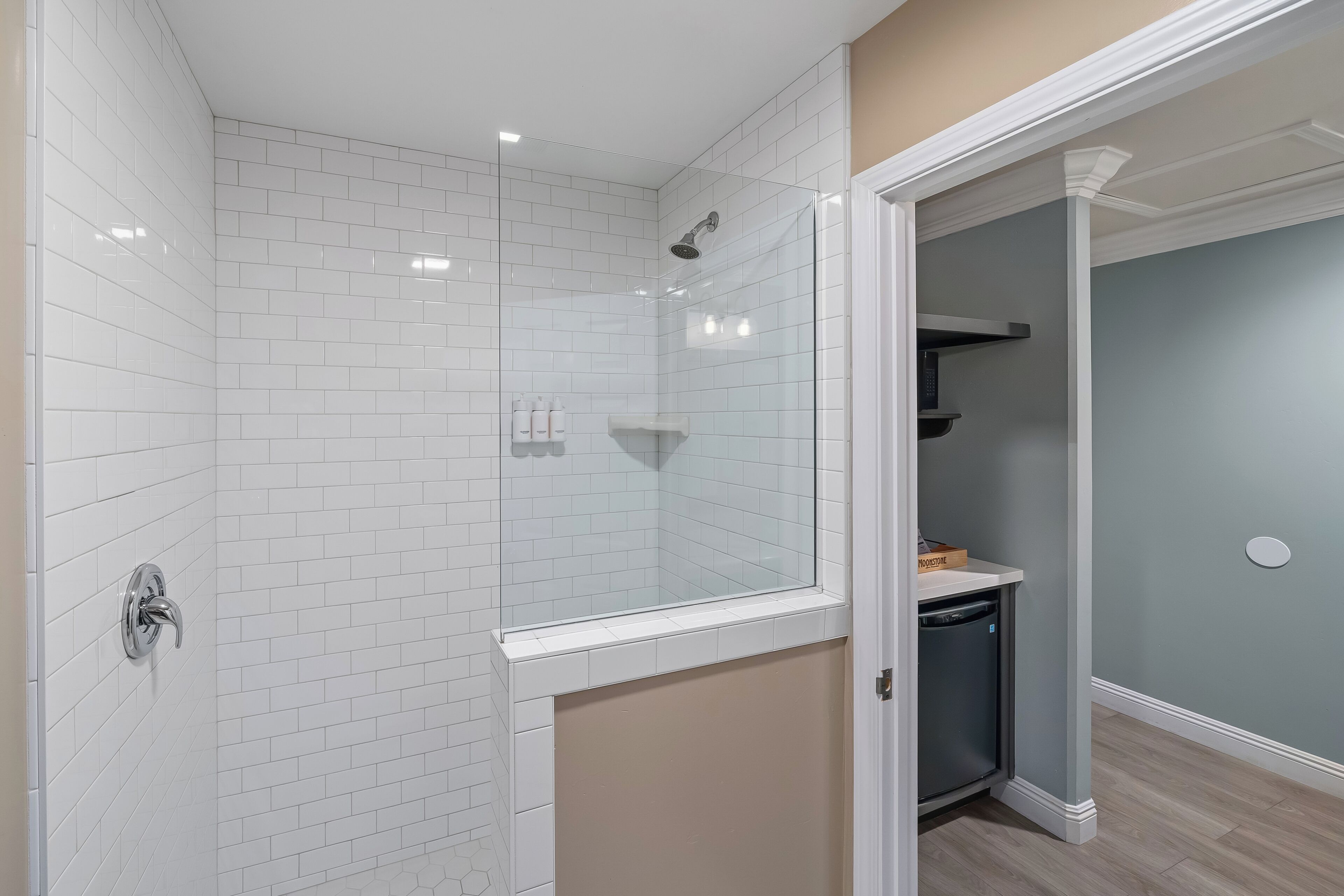 A modern bathroom with white subway tiles, a glass shower enclosure, and a built-in sink.