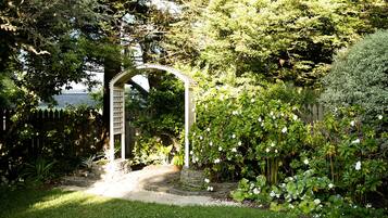 Un jardín con un arco blanco y un camino de piedra que lo conduce.