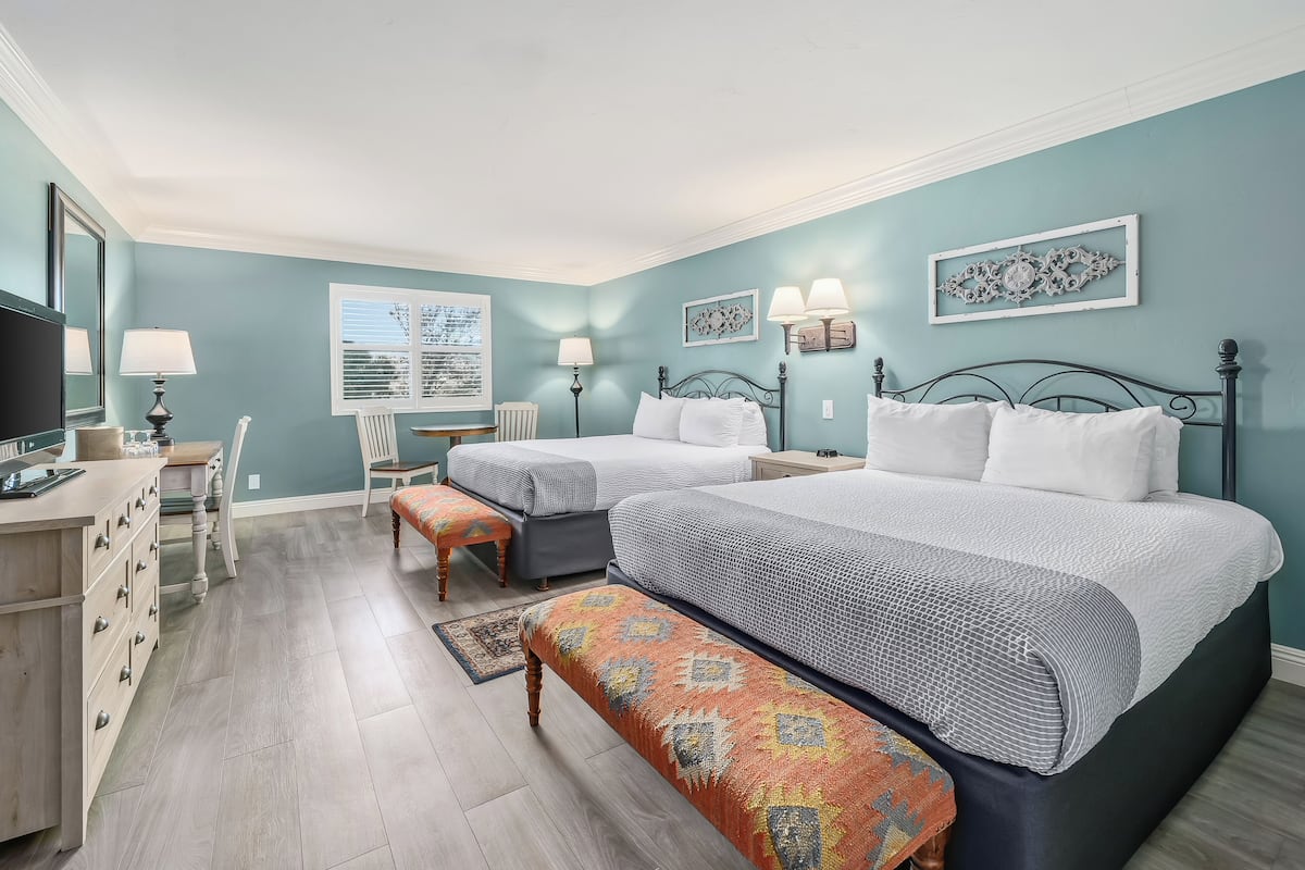 A bedroom with two beds, a desk, a chair, and a window.