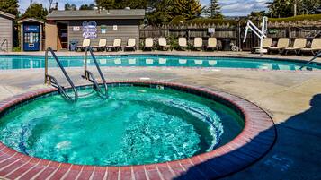 A swimming pool with a hot tub, lounge chairs, and a Pepsi vending machine.