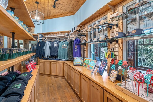Una tienda con estantes de madera, percheros y diversos artículos exhibidos.