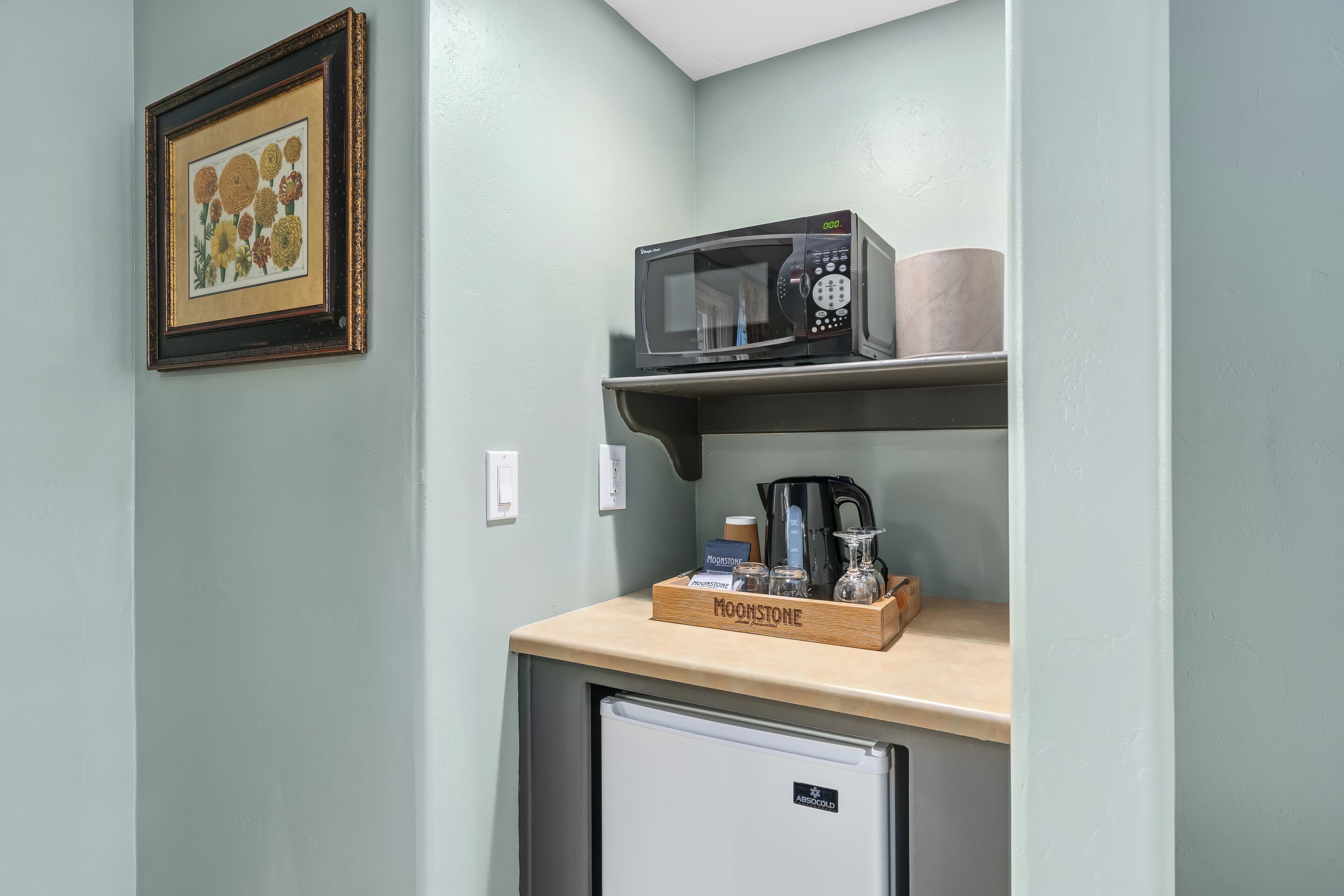 A kitchenette with a microwave, a coffee maker, and a small refrigerator.