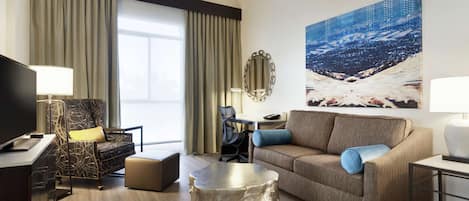 Une chambre d’hôtel moderne dotée d’une grande fenêtre, d’un canapé, d’un bureau et d’une télévision.