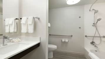 Un baño moderno con un lavamanos blanco, espejo y zona de ducha con cabezal de ducha manual.