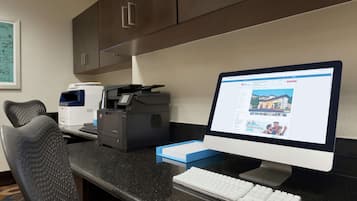 Mostrador de recepción de hotel con una computadora de escritorio, una impresora y un teclado.