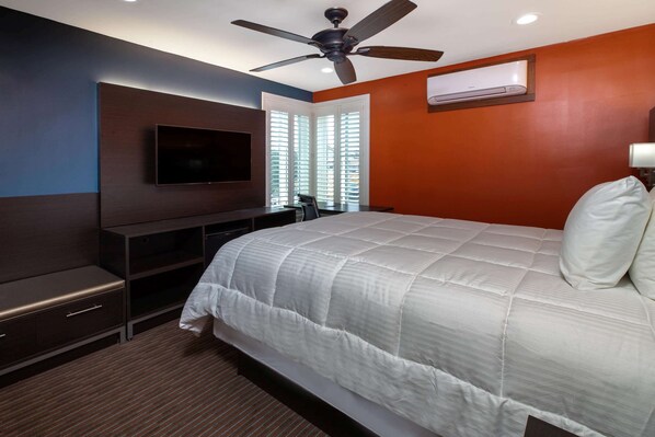 A bedroom with a bed, a TV, a ceiling fan, and an air conditioning unit.