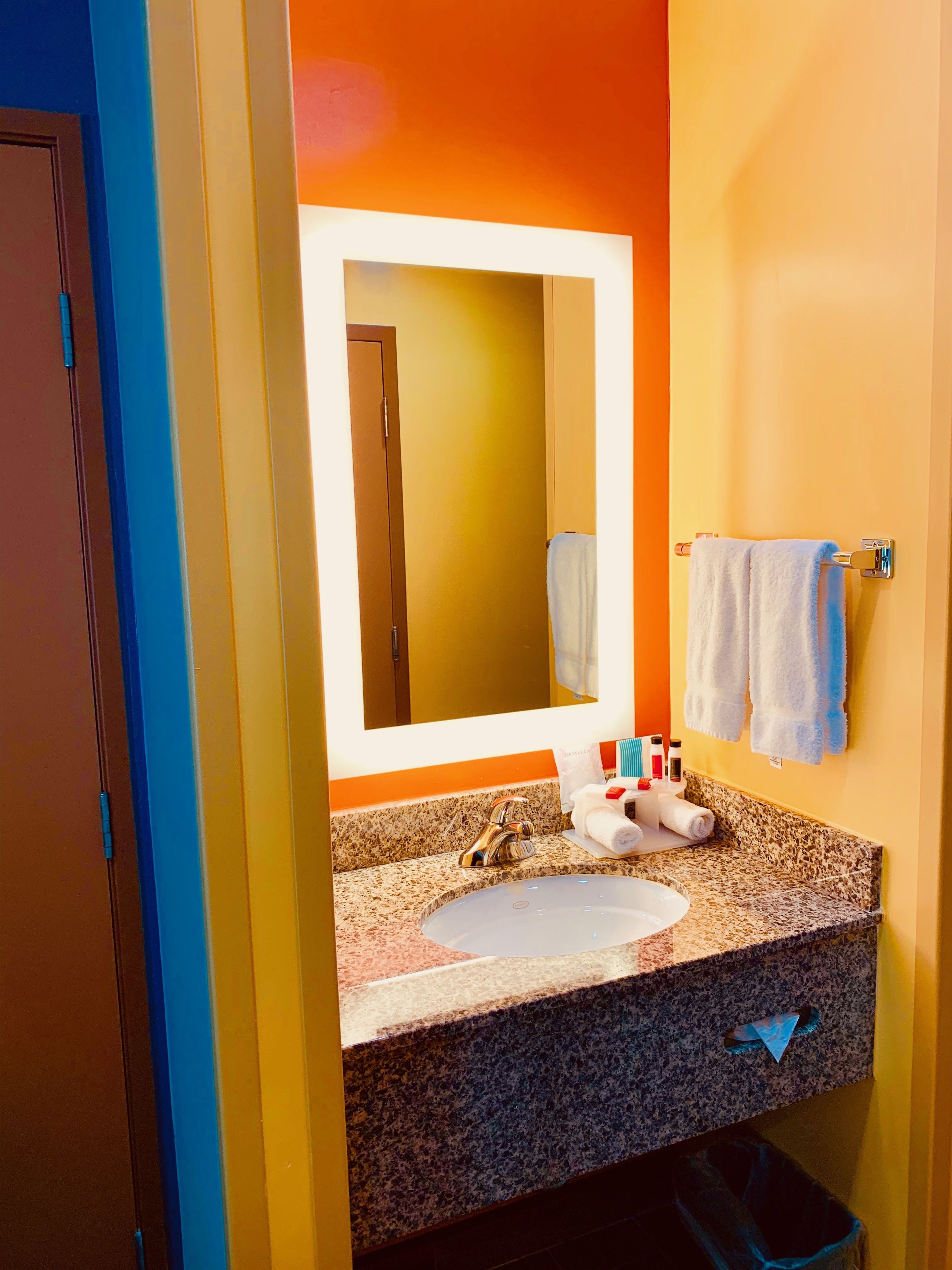 Une salle de bain avec un comptoir en granit, un lavabo, un miroir et un porte-serviettes.