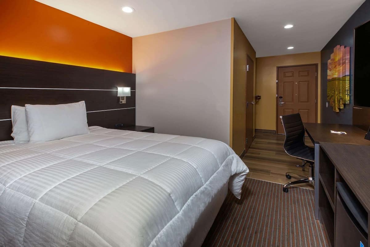 Una habitación de hotel con una cama grande, un escritorio y una silla.